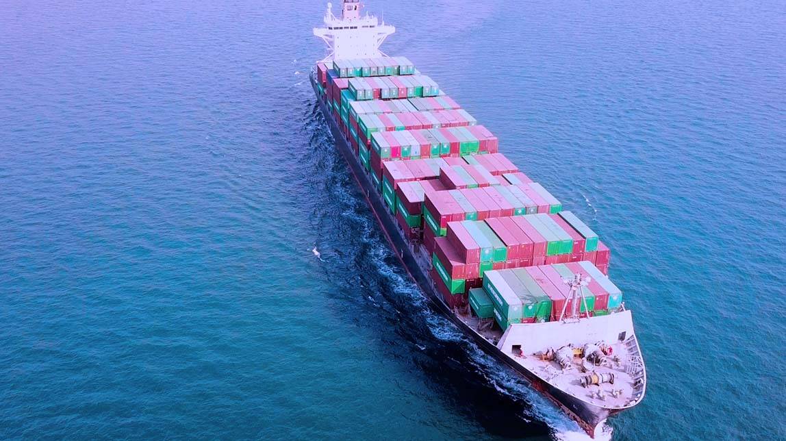 Cargo ship at sea with red and green bins 